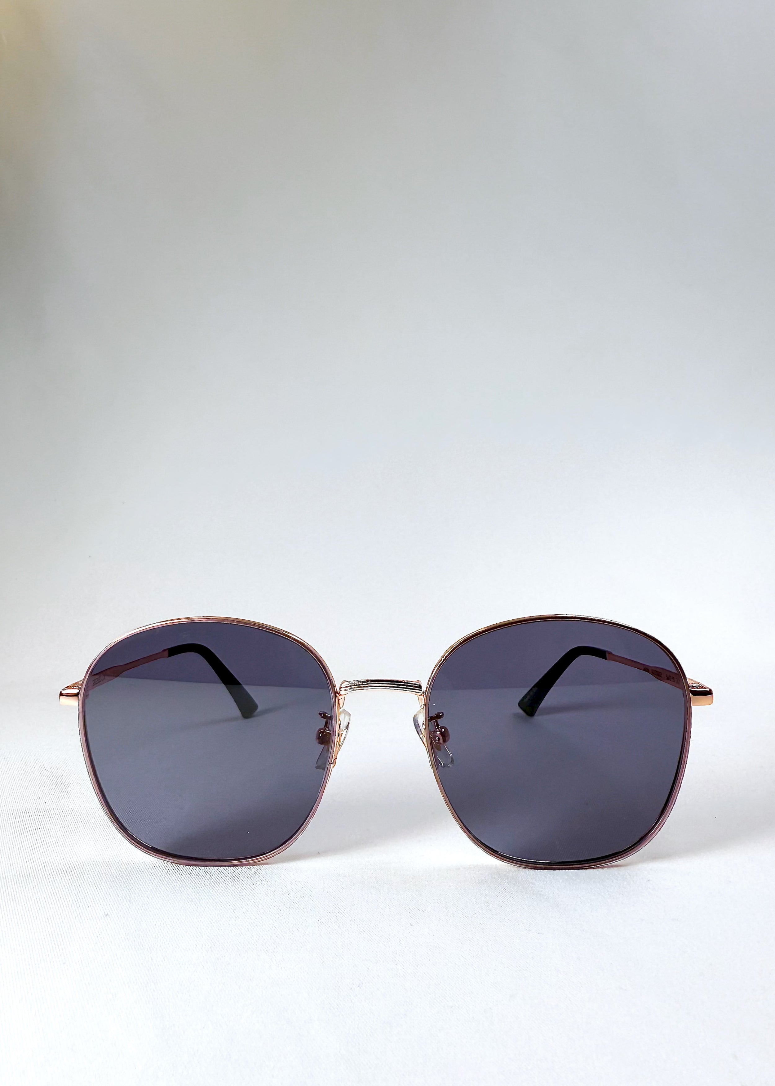 Astris Midnight Blue sunglasses – front view showing full navy lenses and rose gold geometric frame.
