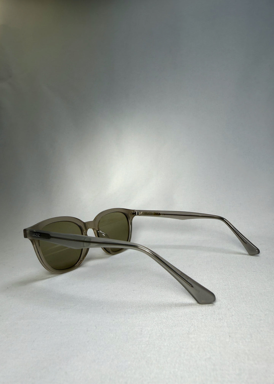 Side-back perspective of Elvor sunglasses in Glacier Smoke, highlighting the fluid design and transparent frame tone.