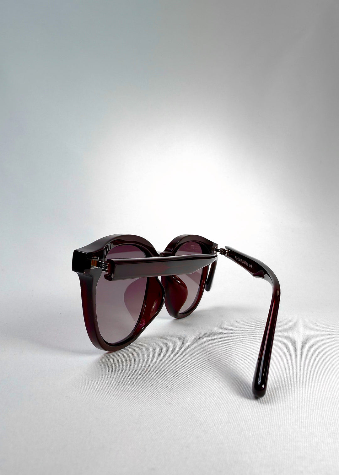 Folded side view of Elvor sunglasses in Mulberry Mist, displaying compact hinges and sculpted arms in translucent burgundy acetate.