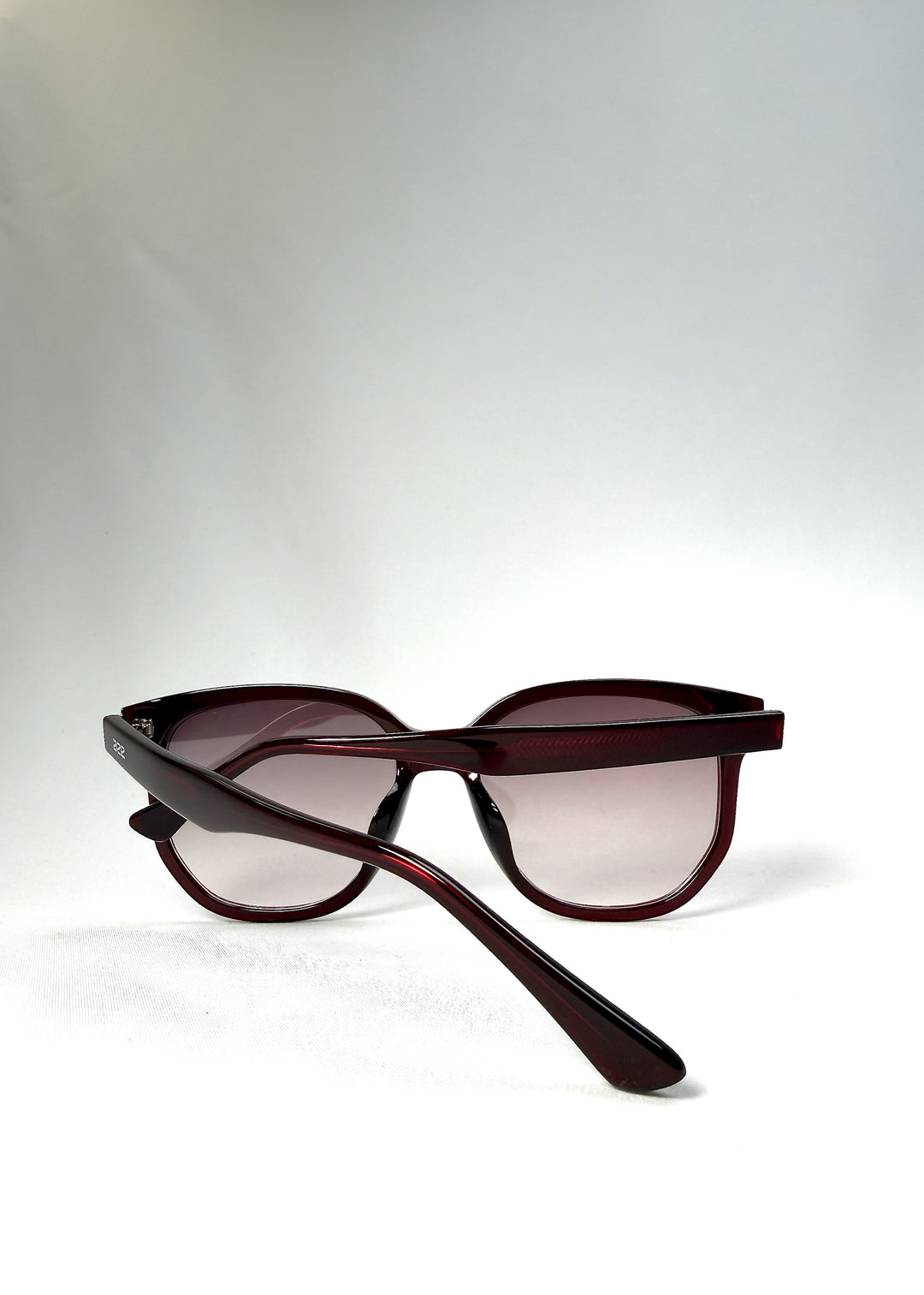 Folded view of Lucent Rift in Velvet Eclipse with arms crossed over the gradient plum lenses.