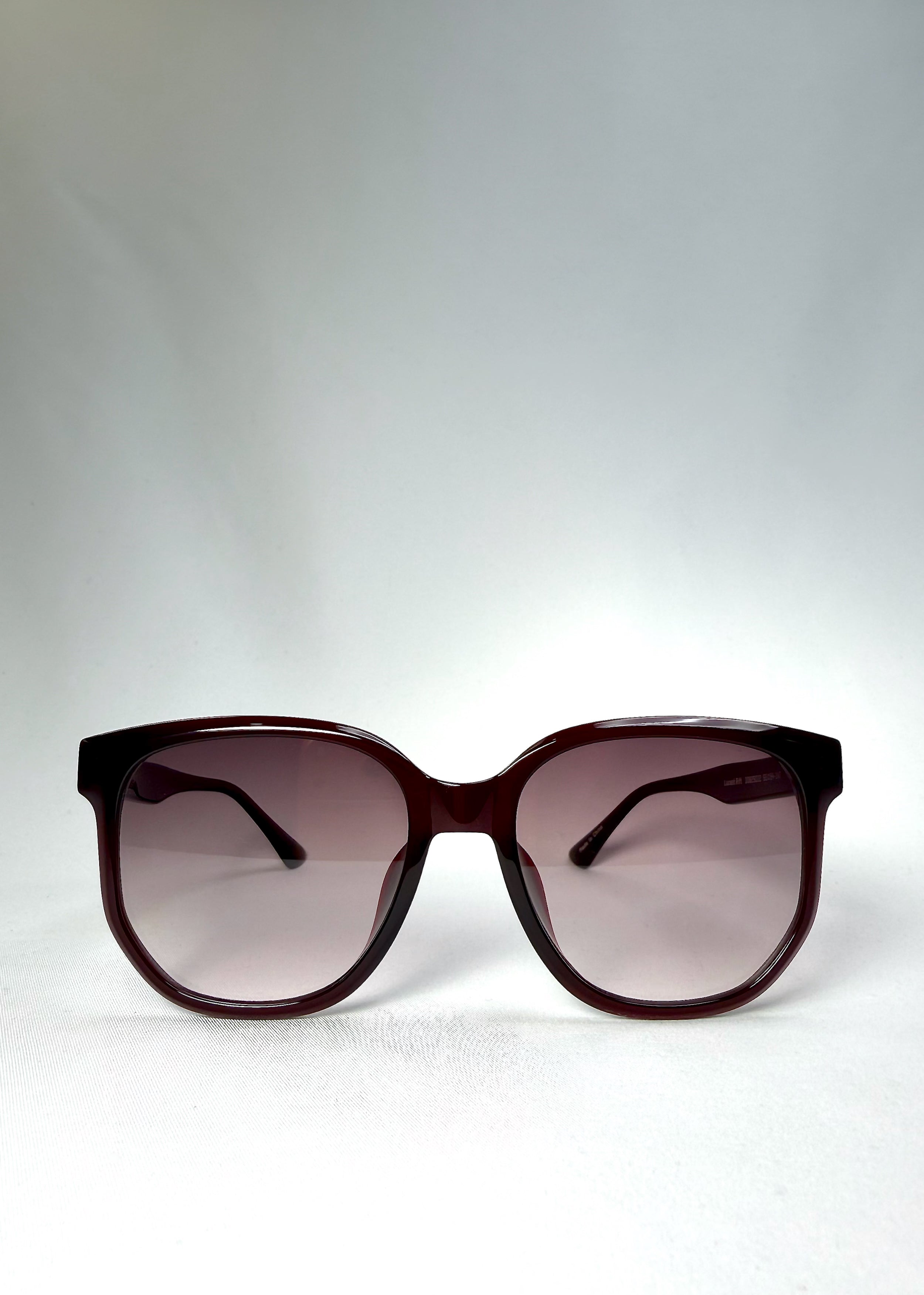 Front view of Lucent Rift in Velvet Eclipse showing the semi-transparent burgundy frame and gradient plum lenses.