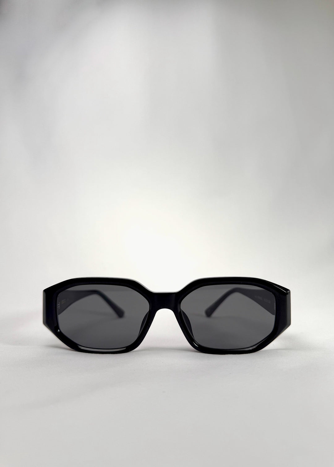 Front view of Lyra glossy black acetate sunglasses – bold angular frame with classic gray lenses.