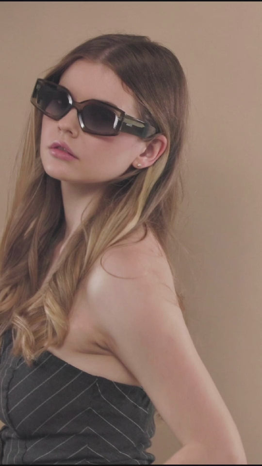 Model wearing Bellatrix Gray Green prescription sunglasses, showcasing the stylish acetate frame with UV400 protection in a natural lighting setting.
