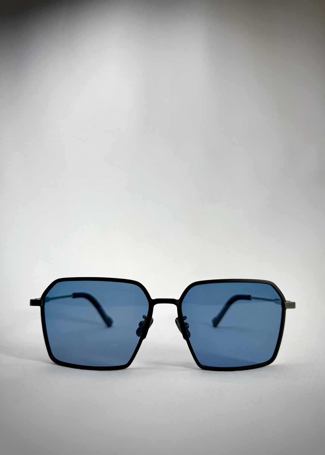 Front view of Rigel matte black titanium prescription sunglasses with a bold square frame and blue-tinted polarized lenses.