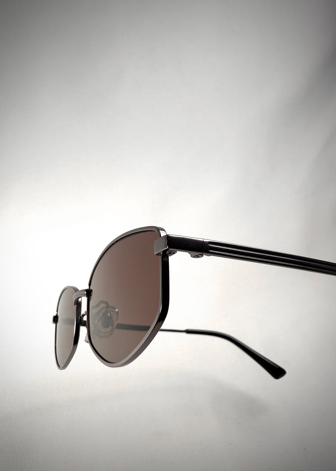 Close-up hinge view of Sirius B Gunmetal Amber sunglasses – Precision-crafted gunmetal frame with warm amber-tinted lenses and sleek temple detailing.
