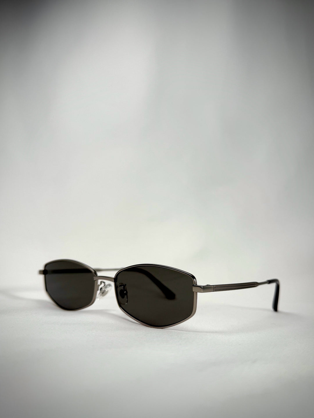 Side angle of Sirius B Gunmetal sunglasses, showcasing the sleek stainless steel frame and premium green lenses.