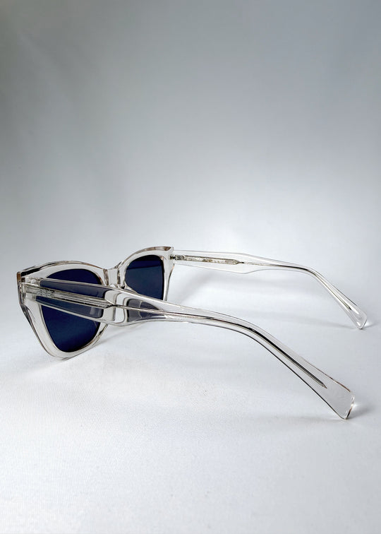 Side and temple view of the Veyron sunglasses in Crystal Static, showcasing the sculptural clear acetate arms and slate-blue polarized lenses.