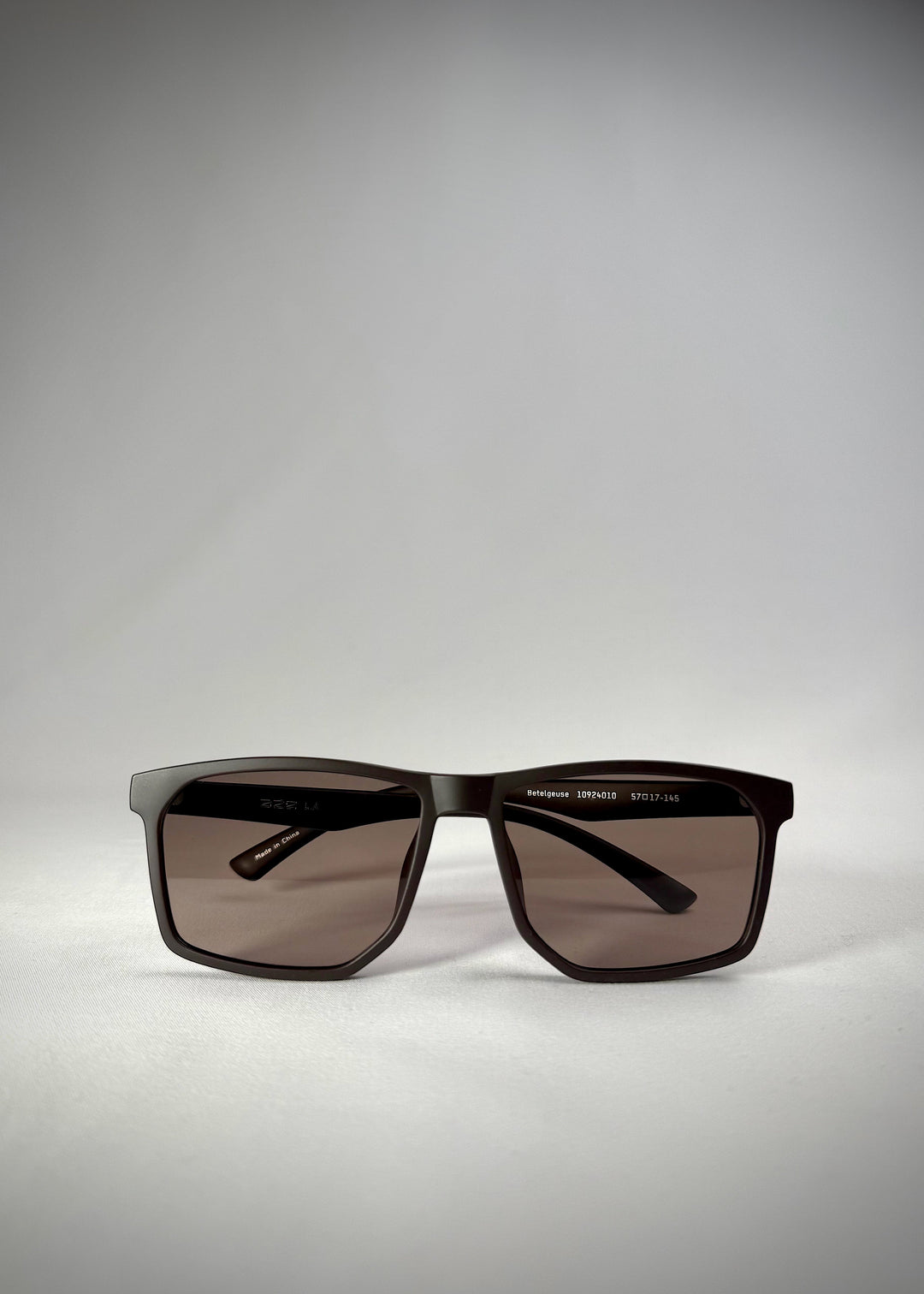 Low front view of Betelgeuse matte brown TR90 sunglasses, showing the rectangular frame and warm brown gradient lenses. 