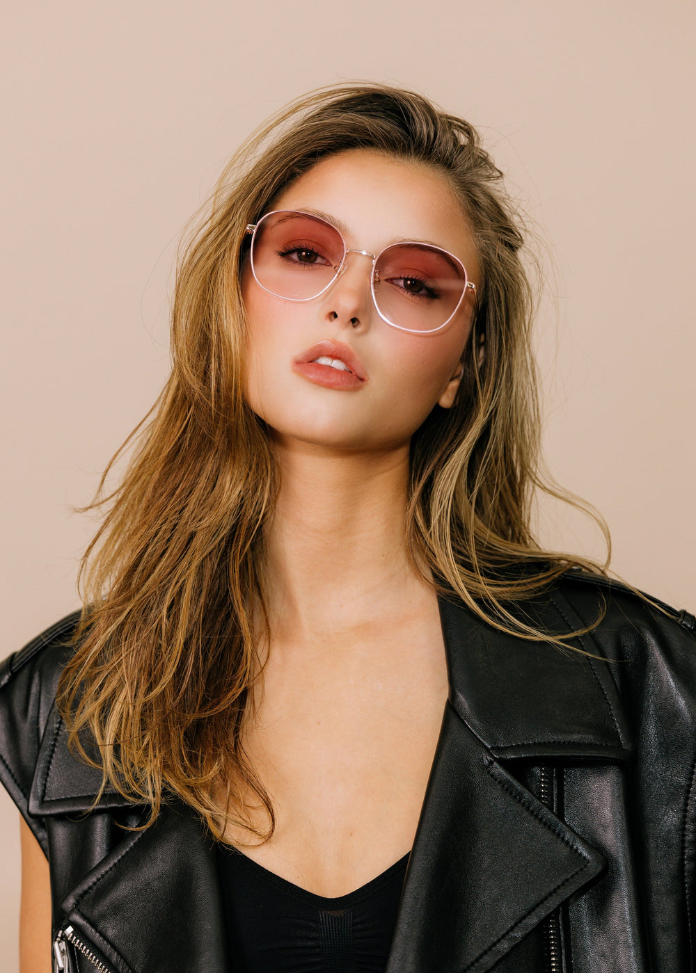 Model wearing Astris sunglasses in Rosé Dawn, facing forward to show the rose gold frame and blush gradient lenses. #color_ros-dawn