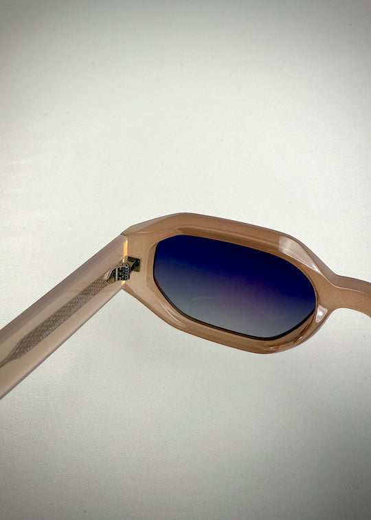 Close-up of Castor Champagne sunglasses – detailed view of acetate frame, metal hinge, and gradient blue lenses. 