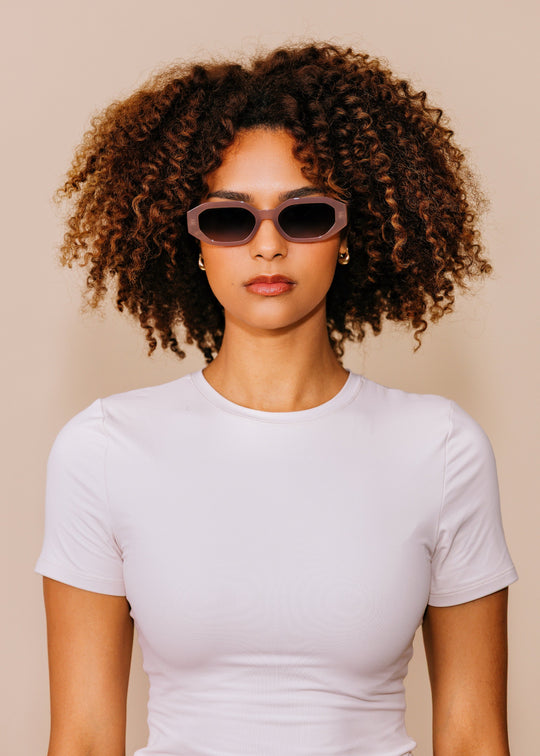 Female model wearing Castor sunglasses in Champagne with a white T-shirt, highlighting the softly translucent frame. 