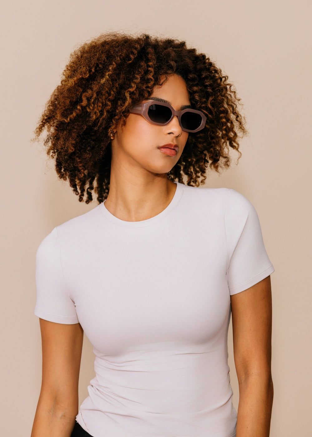 Female model wearing Castor sunglasses in Champagne, showing the geometric acetate frame and blue gradient lenses.