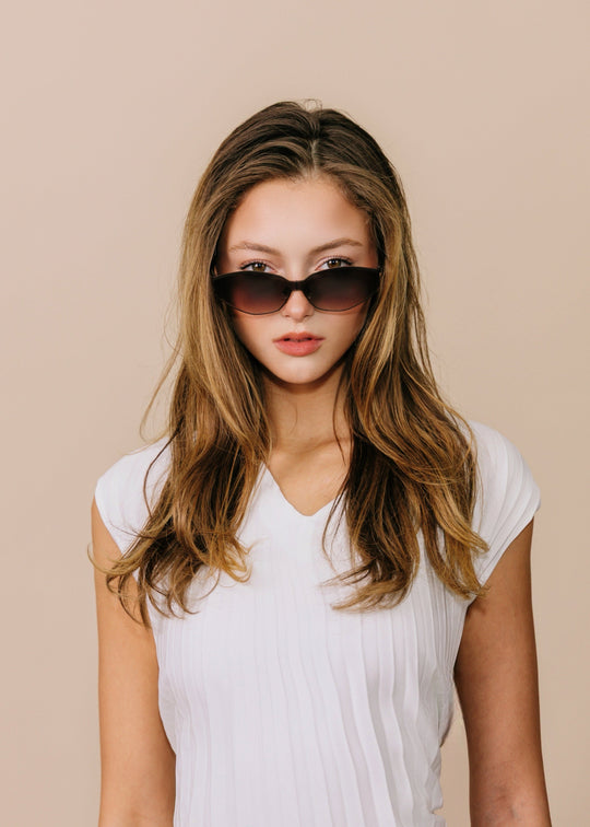 Model wearing Celestia – Ash Fade with a white top, showing the rose-gold browline and soft brown gradient lenses. 