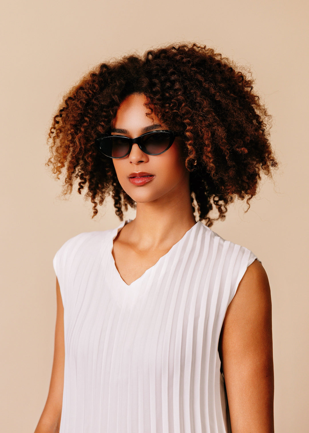 Female model wearing Chara sunglasses in Black with a white ribbed sleeveless top, facing forward. 