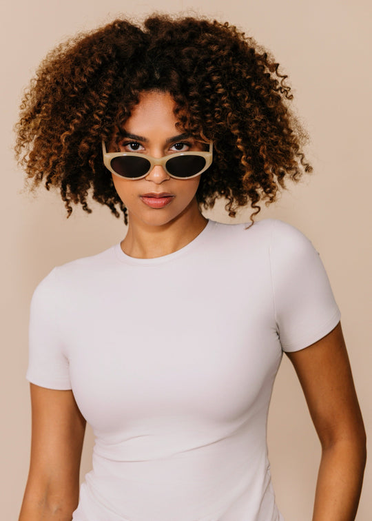 Female model wearing Chara sunglasses in Milky White with a white top, facing forward. 