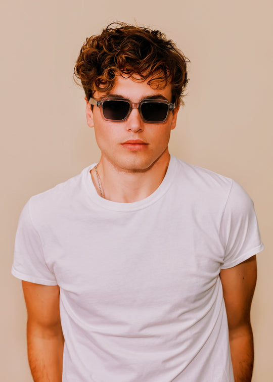 Man wearing sunglasses and a white t-shirt against a beige background 