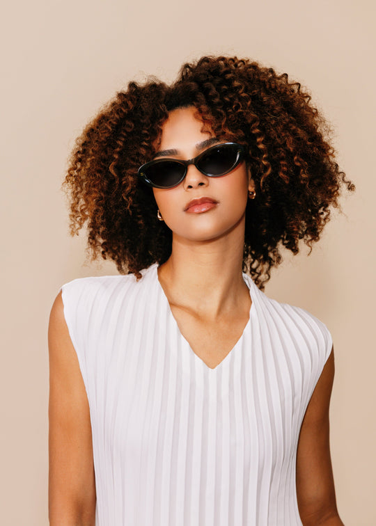 Front portrait of a model wearing Dagger sunglasses in Obsidian Black with a white sleeveless top. 