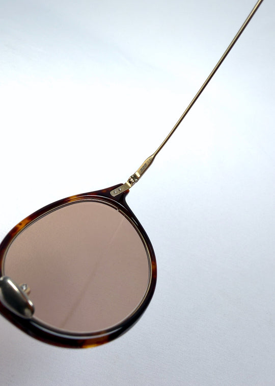Close-up of Lunor Drift Softint sunglasses in Umber Fade showing the acetate lens rim and titanium hinge construction. 