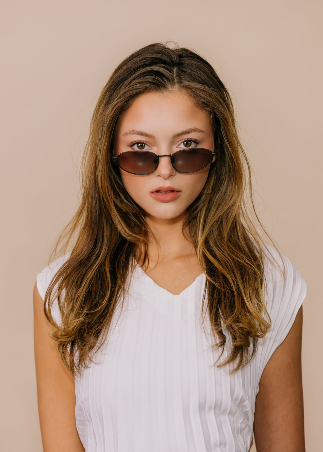 Model wearing Lunaris - Dusk Bronze sunglasses facing forward, showing the bronze frame line and soft tea-tinted lens gradient. 
