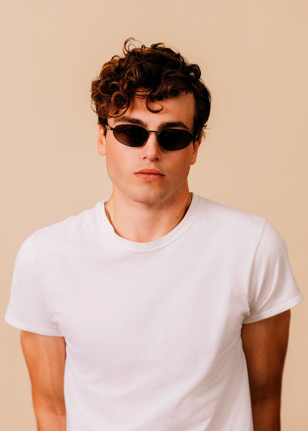 Model wearing Lunaris - Dusk Bronze sunglasses facing forward, showing how the narrow bronze frame sits across the face. 