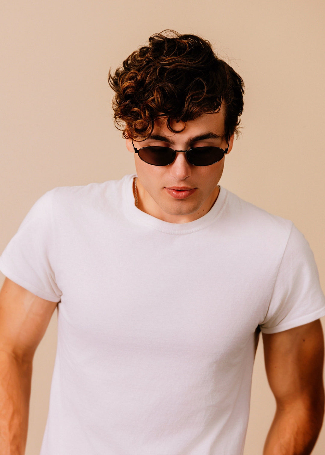 Model wearing Lunaris - Dusk Bronze sunglasses, head tilted down to show the low-profile bronze frame and gradient tea lenses. 