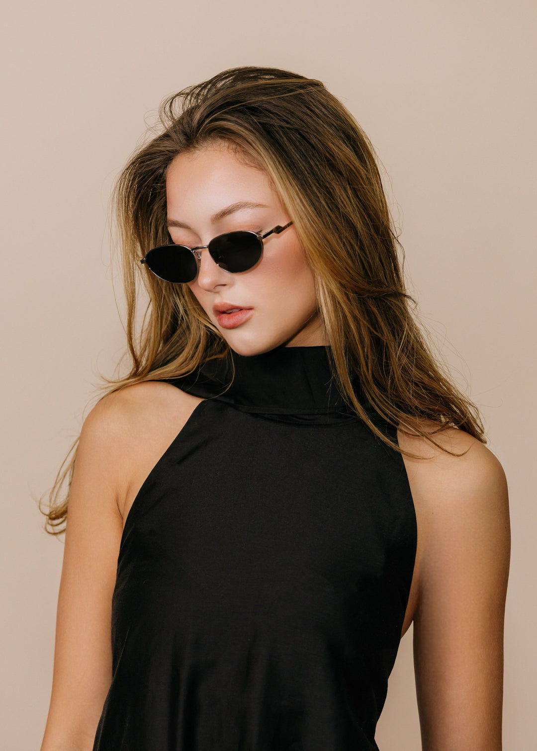 Model wearing Lunaris - Moonlit Silver sunglasses in three-quarter profile, showing the thin silver temples and low-profile lens shape. 