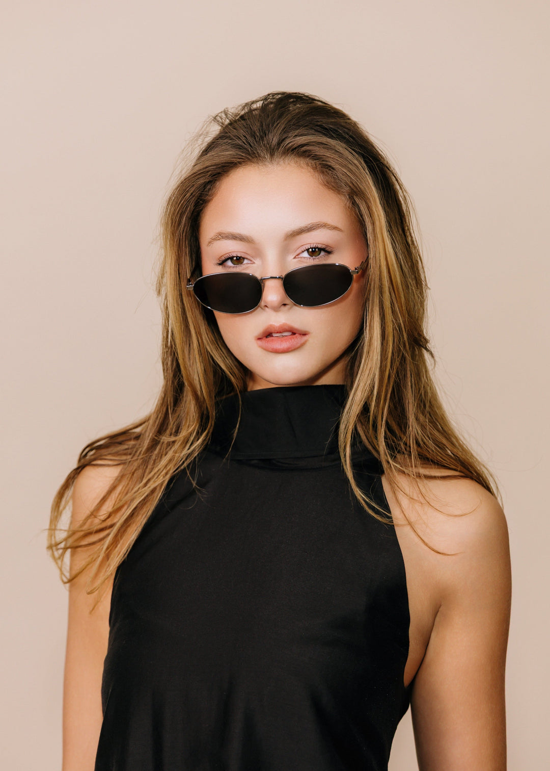 Model wearing Lunaris - Moonlit Silver sunglasses, facing forward to show the slim silver metal frame and dark grey lenses. 