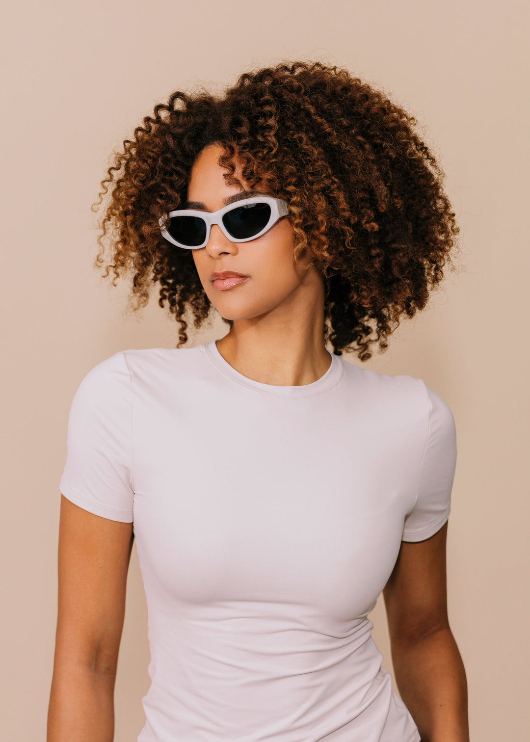 Model wearing Nebula Shade sunglasses in Glacial Ash, turned to show the fog-white frame and wide temple in profile. 
