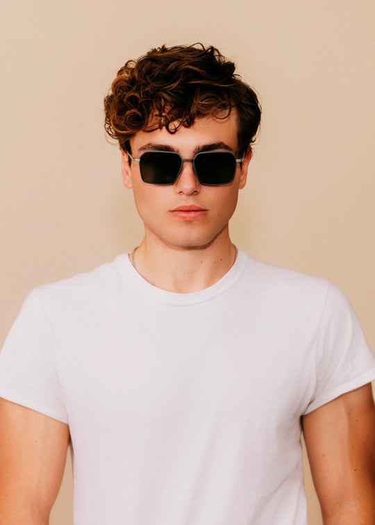 Male model wearing Rigel sunglasses in Olive Smoke with a white t-shirt, facing forward. 