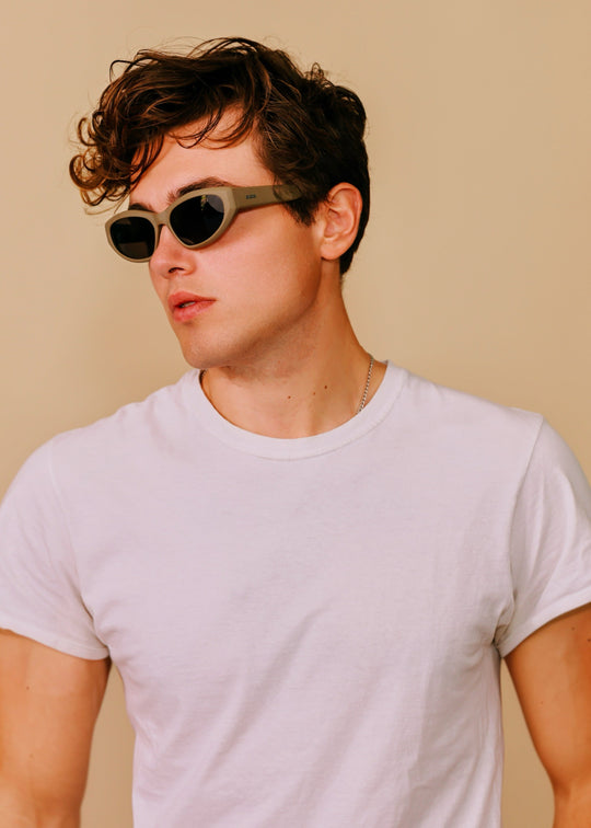 Man wearing Void Striker sunglasses in Bronze Mirage with a white T-shirt against a warm beige background. 