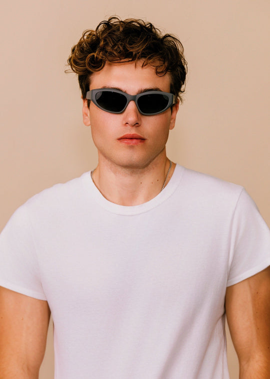 Man wearing sunglasses and a white t-shirt against a beige background 