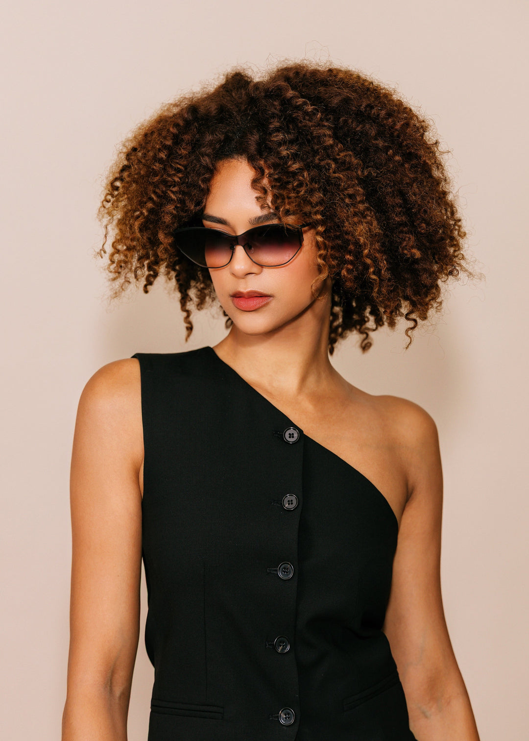 Model wearing Zenith sunglasses in Midnight Eclipse with a black one-shoulder dress against a neutral beige background. 