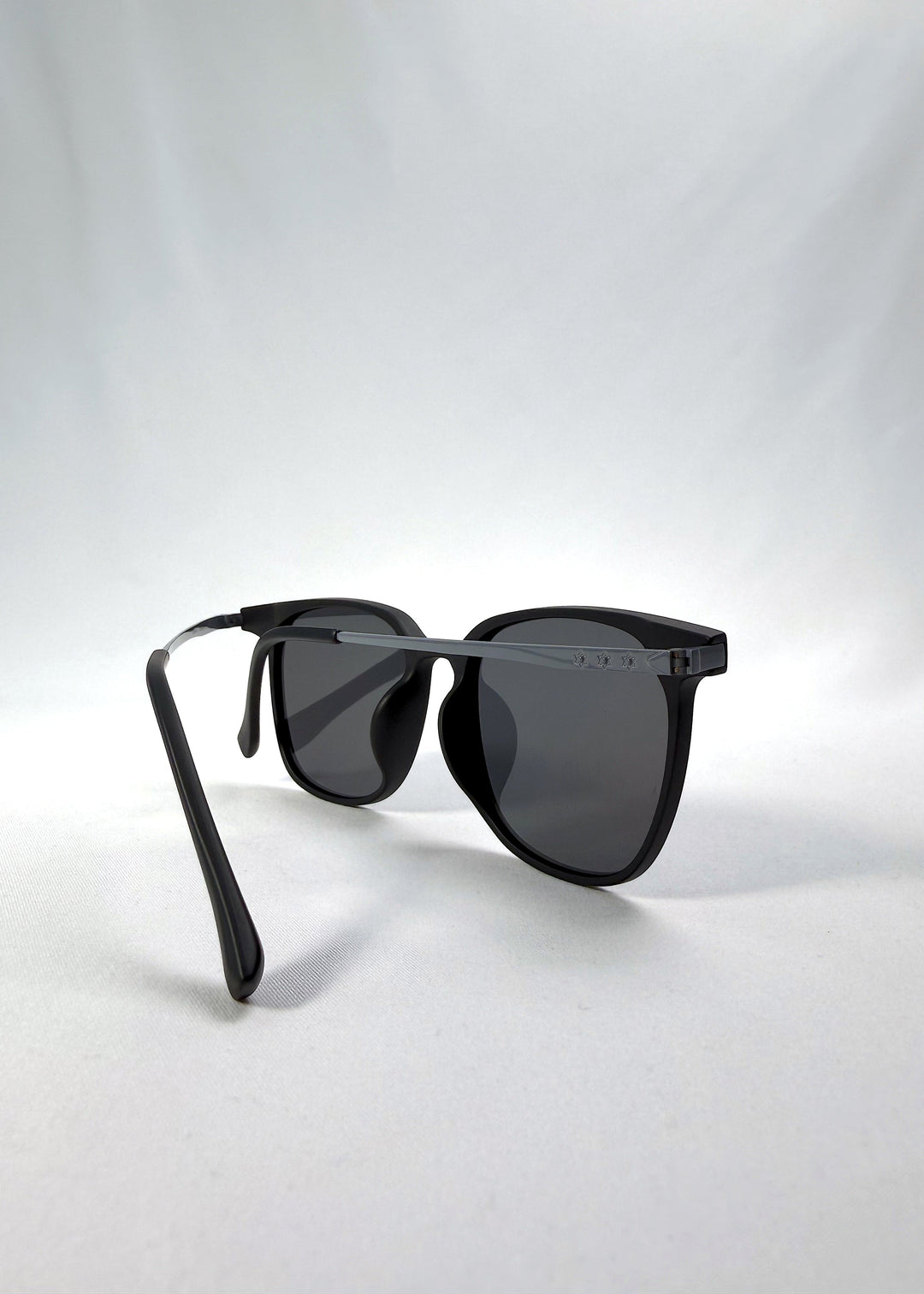 Back-angle view of Achernar sunglasses in Classic Black, featuring an ultra-light frame with titanium temples, softly geometric lens shape, and polarized lenses, showing the back structure and temple alignment. 
