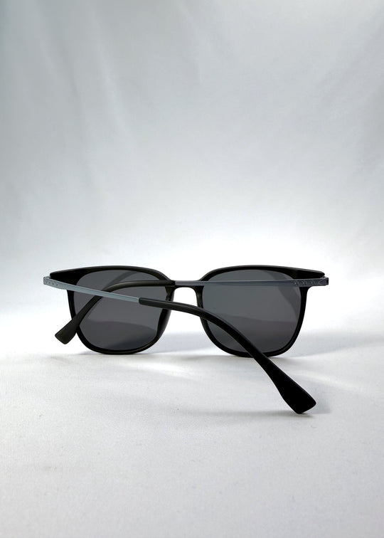 Folded view of Achernar sunglasses in Classic Black, featuring ultra-light titanium frame, softly geometric lens shape, and polarized lenses, showing the folded temples and frame profile.