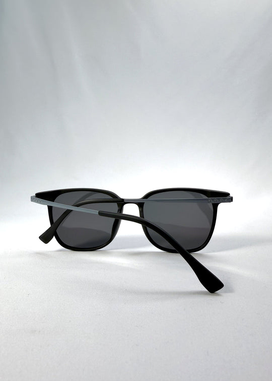 Folded view of Achernar sunglasses in Classic Black, featuring an ultra-light frame with titanium temples, softly geometric lens shape, and polarized lenses, showing the folded temples and frame profile. 