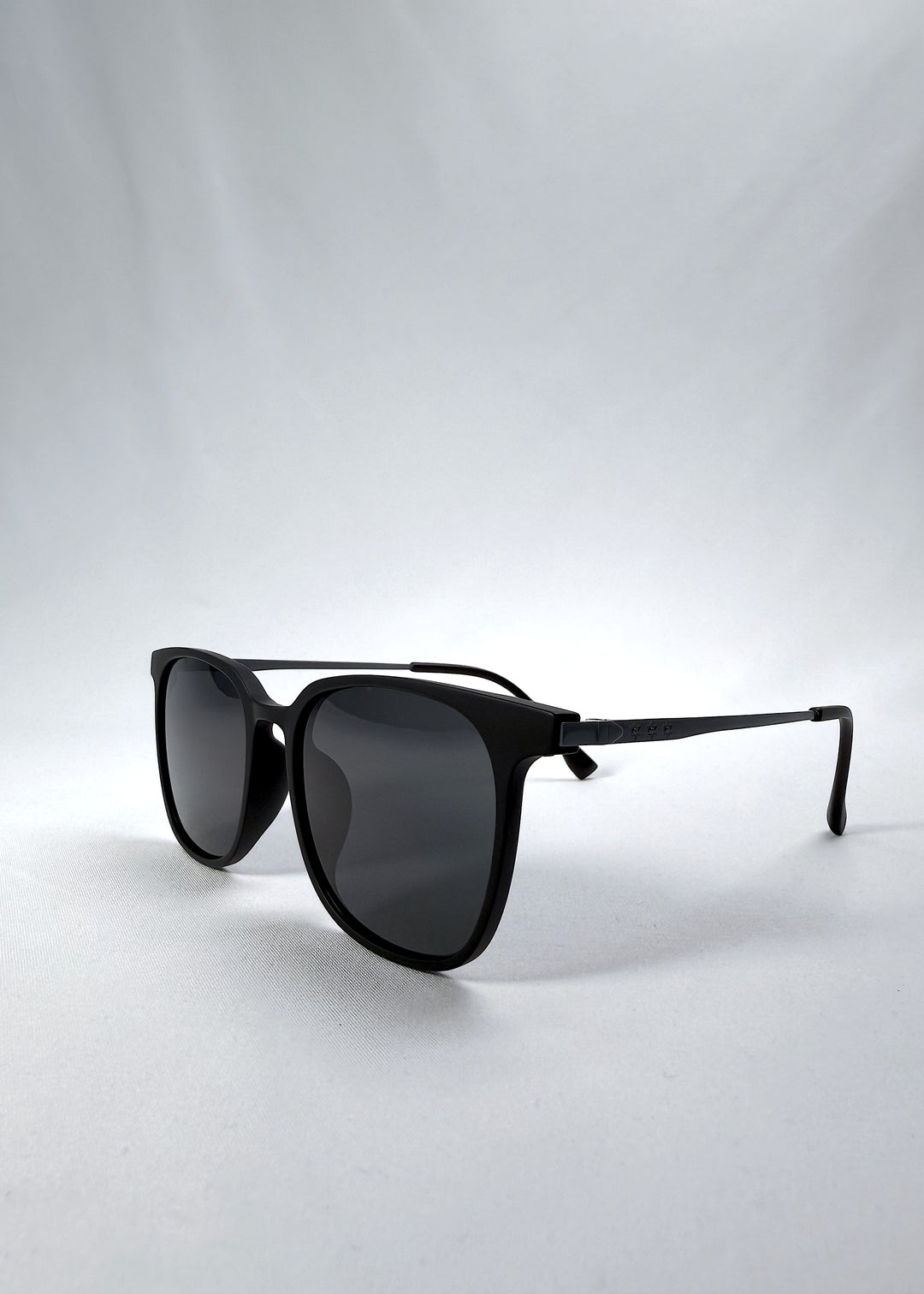 Three-quarter front view of Achernar sunglasses in Classic Black, featuring ultra-light titanium frame, softly geometric lens shape, and polarized lenses, showing the front shape and temple profile.