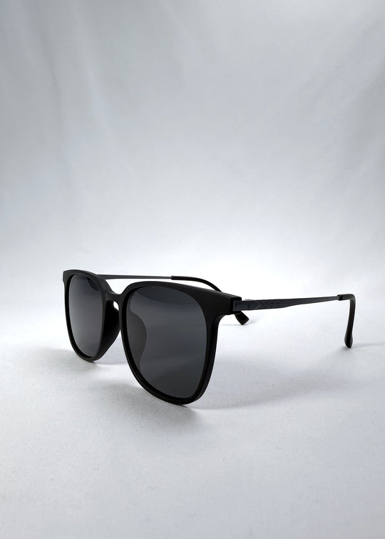 Three-quarter front view of Achernar sunglasses in Classic Black, featuring ultra-light titanium frame, softly geometric lens shape, and polarized lenses, showing the front shape and temple profile.