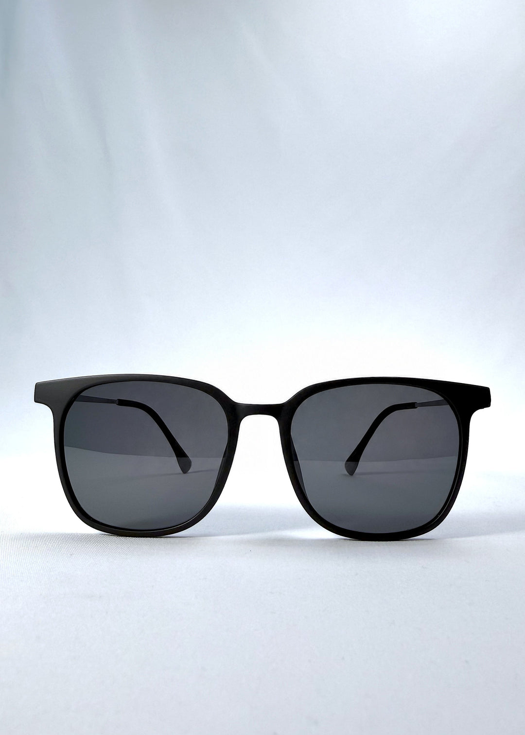 Front view of Achernar sunglasses in Classic Black, featuring an ultra-light frame with titanium temples, softly geometric lens shape, and polarized lenses, showing the full front silhouette. 