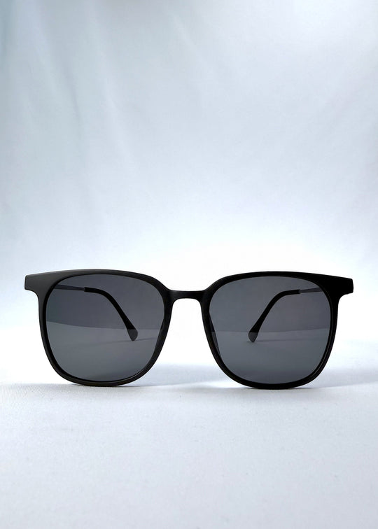 Front view of Achernar sunglasses in Classic Black, featuring an ultra-light frame with titanium temples, softly geometric lens shape, and polarized lenses, showing the full front silhouette. 