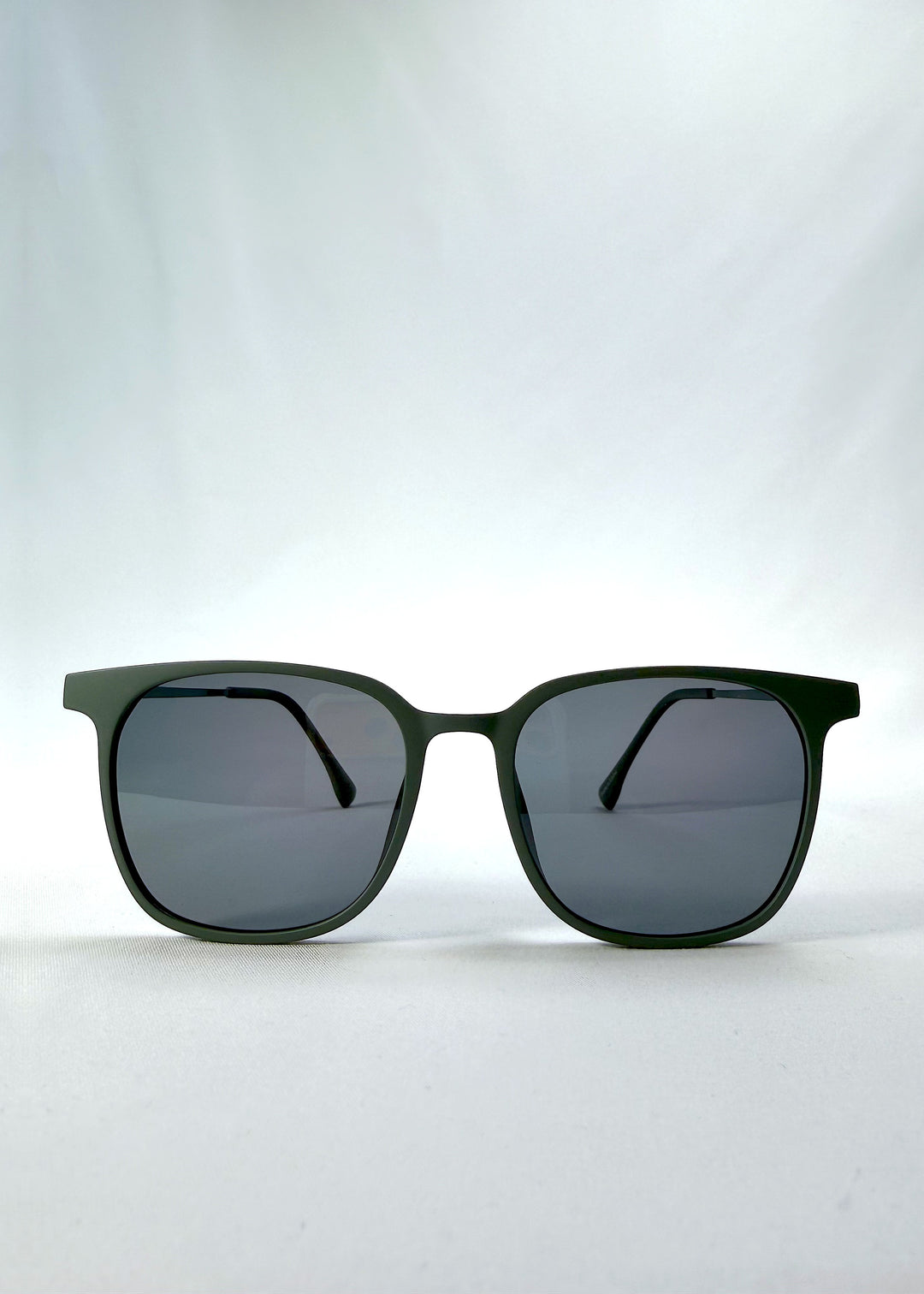 Front view of Achernar sunglasses in Deep Matte Green, featuring ultra-light titanium frame, softly geometric lens shape, and polarized lenses, showing the full front silhouette.