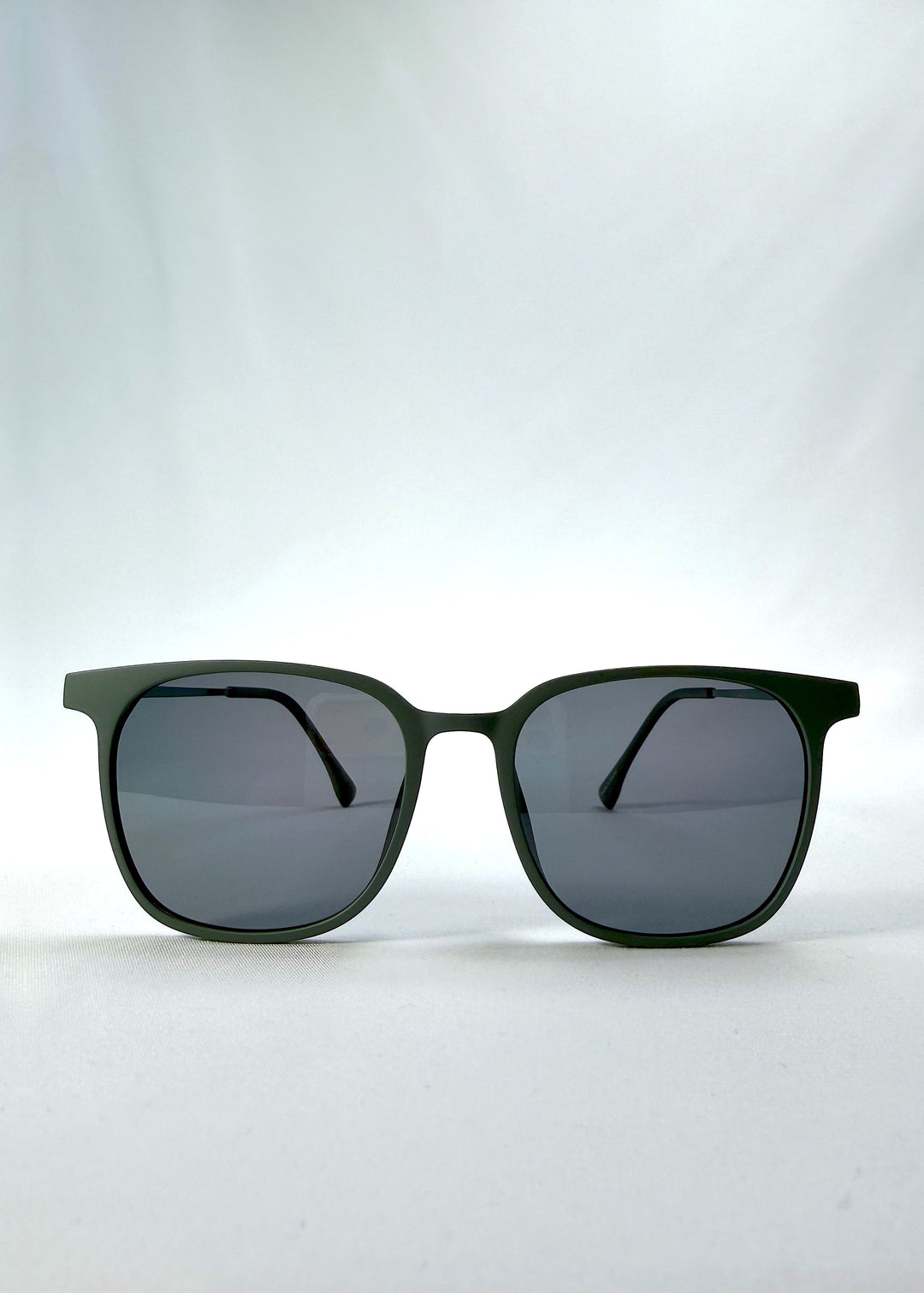 Front view of Achernar sunglasses in Deep Matte Green, featuring an ultra-light frame with titanium temples, softly geometric lens shape, and polarized lenses, showing the full front silhouette. 