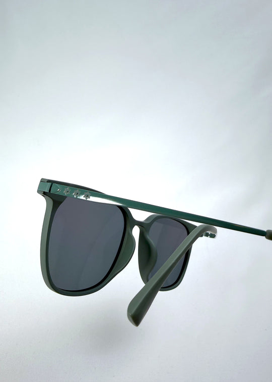 Close-up temple detail view of Achernar sunglasses in Deep Matte Green, featuring ultra-light titanium frame, softly geometric lens shape, and polarized lenses, showing the temple arm and hinge area.