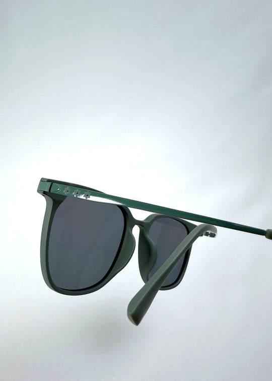Close-up temple detail view of Achernar sunglasses in Deep Matte Green, featuring an ultra-light frame with titanium temples, softly geometric lens shape, and polarized lenses, showing the temple arm and hinge area. 