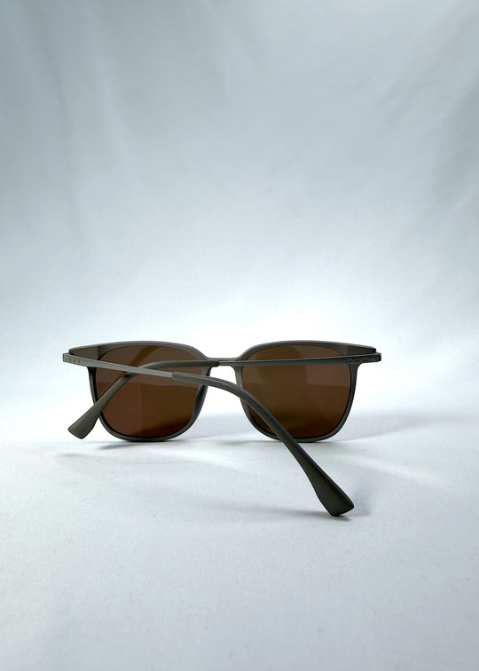 Folded view of Achernar sunglasses in Khaki Brown, featuring ultra-light titanium frame, softly geometric lens shape, and polarized lenses, showing the folded temples and frame profile.