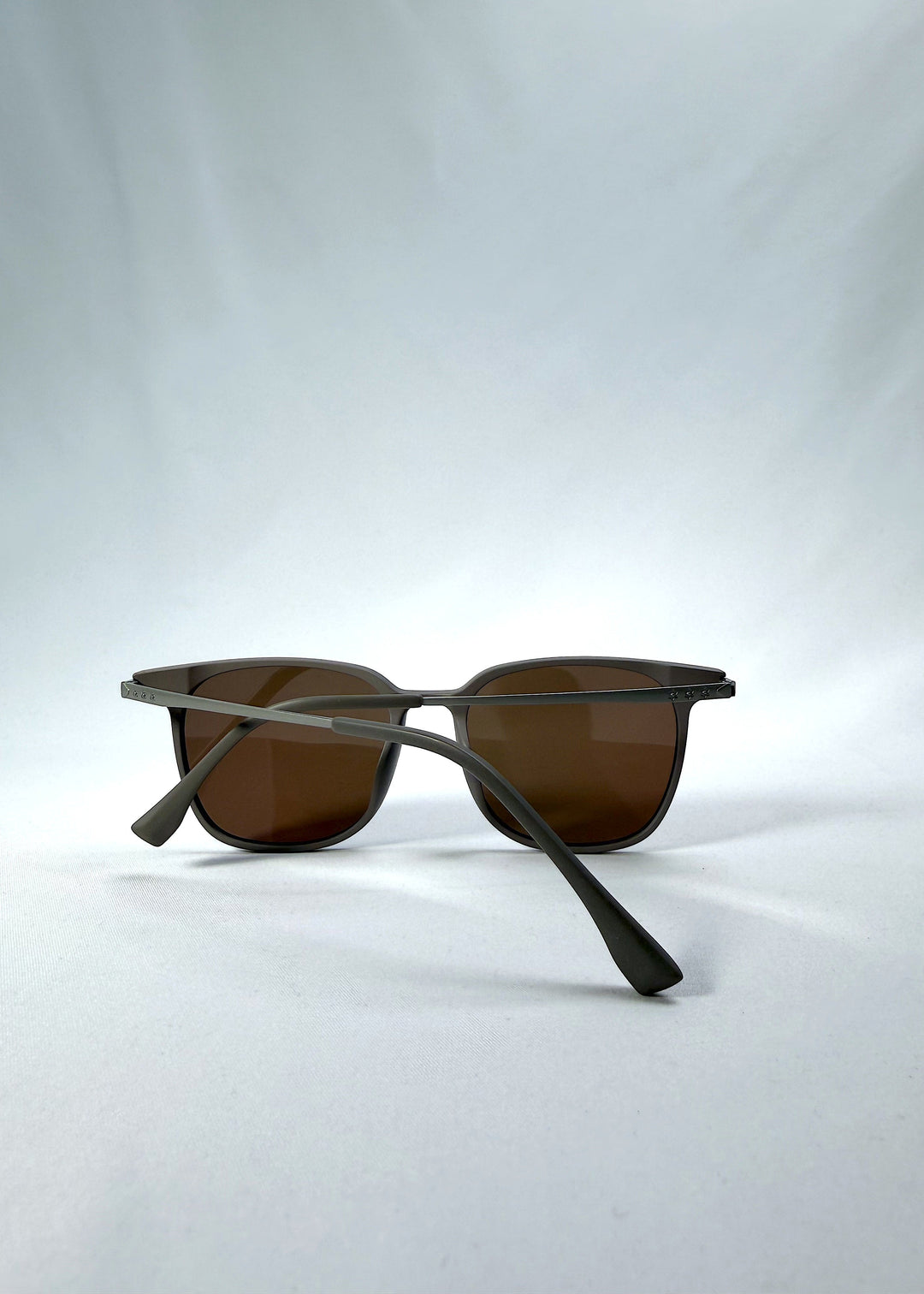 Folded view of Achernar sunglasses in Khaki Brown, featuring an ultra-light frame with titanium temples, softly geometric lens shape, and polarized lenses, showing the folded temples and frame profile. 