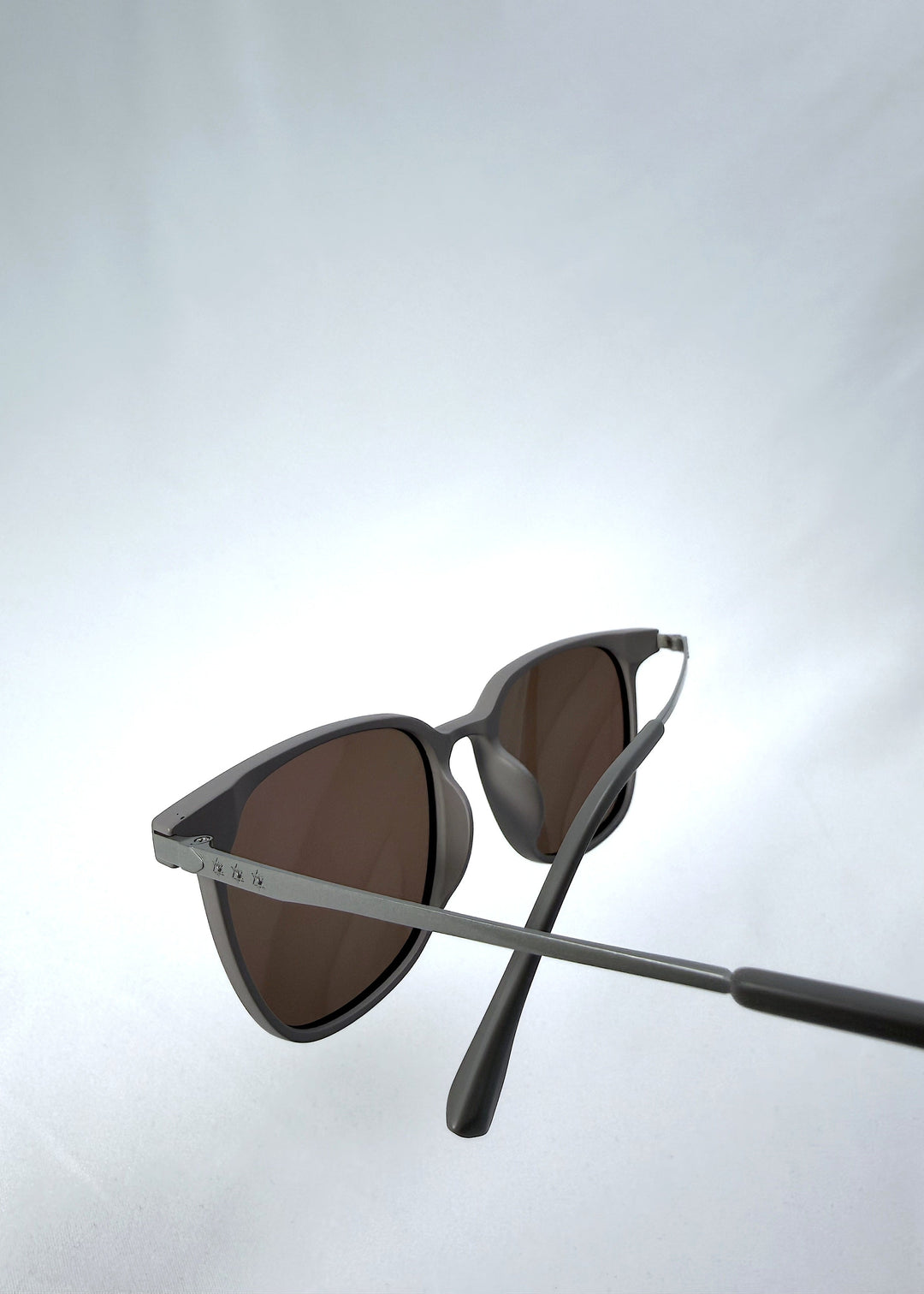Close-up temple detail view of Achernar sunglasses in Khaki Brown, featuring an ultra-light frame with titanium temples, softly geometric lens shape, and polarized lenses, showing the temple arm and hinge area. 