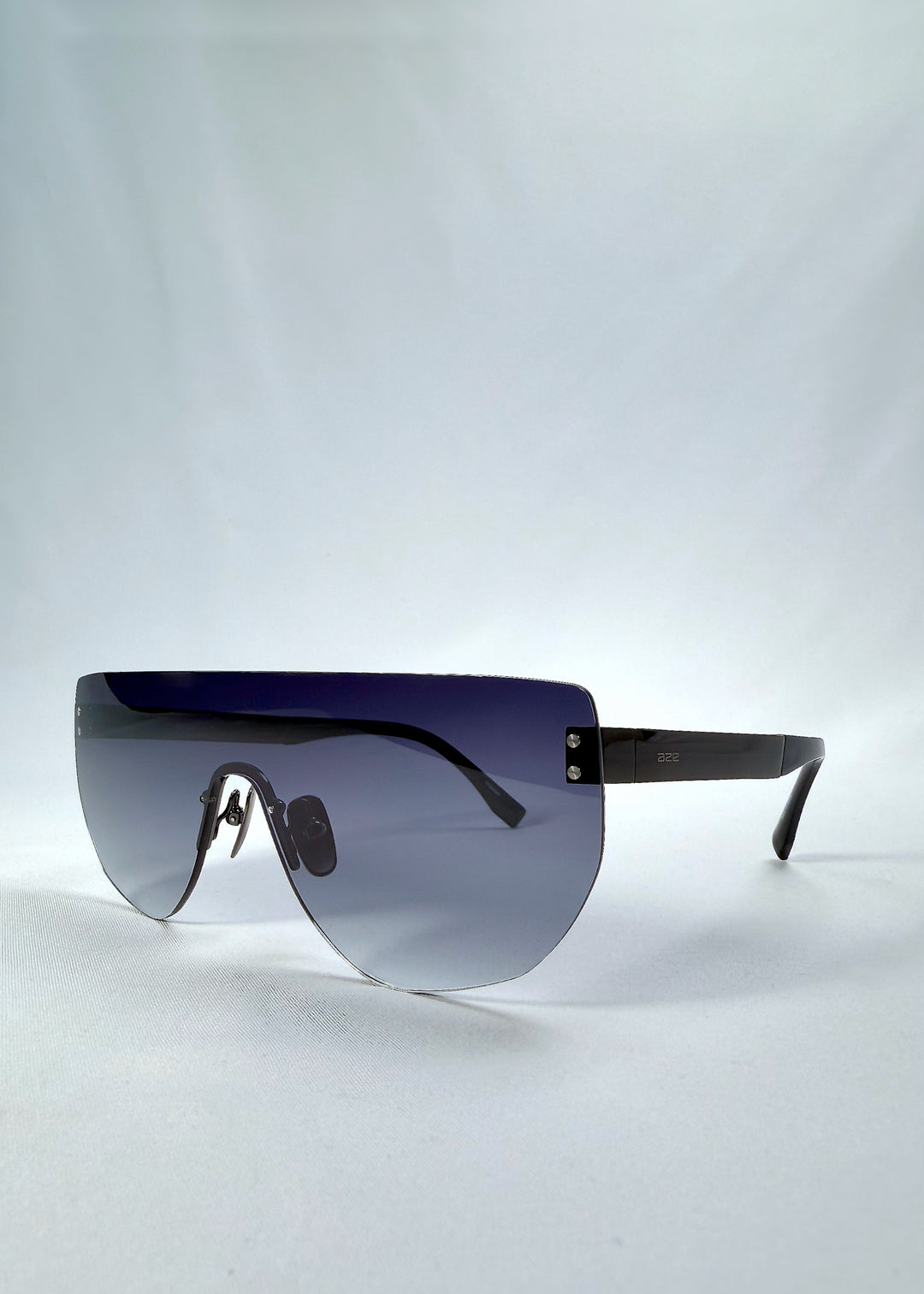 Three-quarter front view of Aegis Field sunglasses in Gunmetal Veil, featuring one-piece titanium shield frame and gunmetal-to-grey gradient lens, showing the front shape and temple profile.