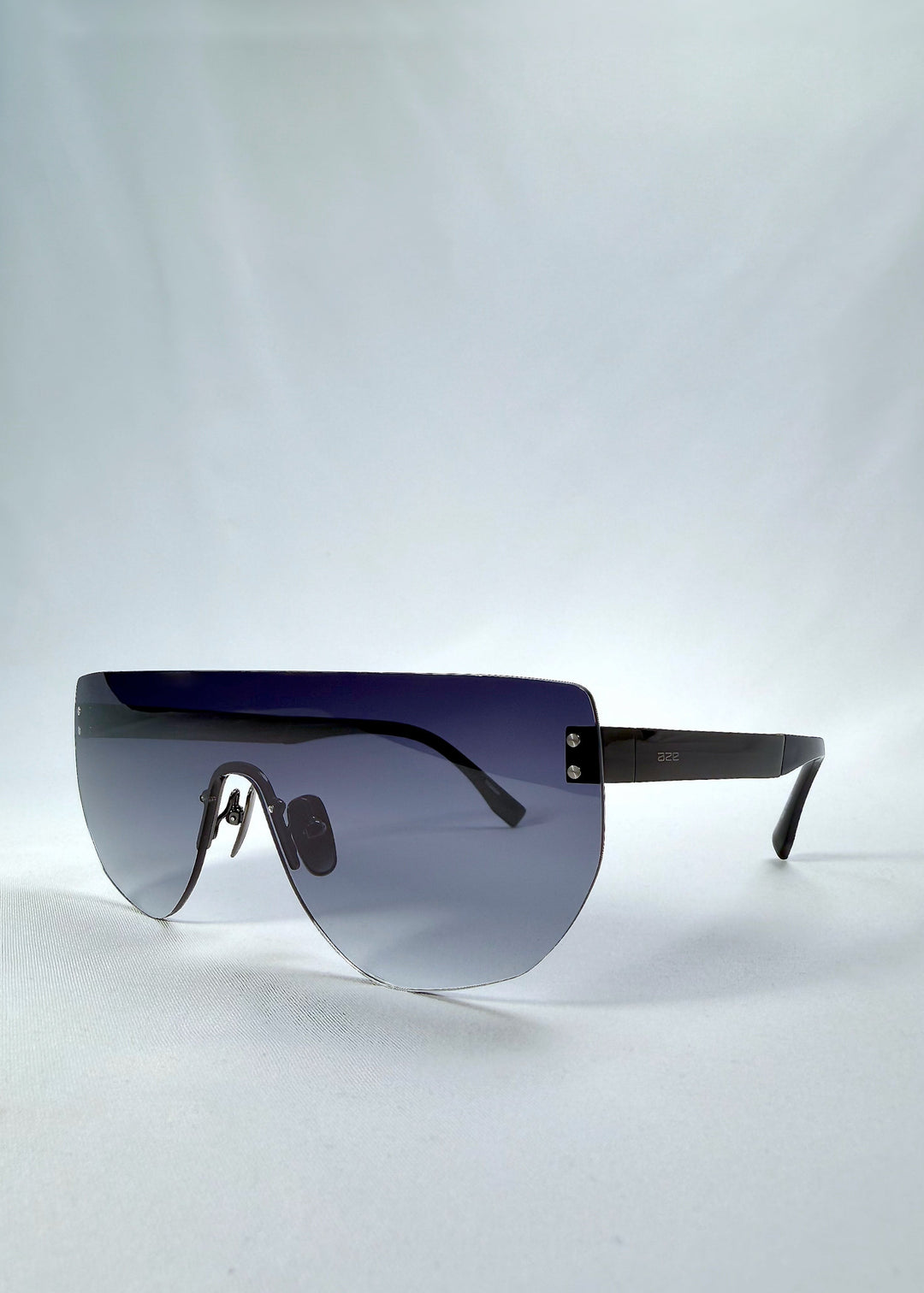 Three-quarter front view of Aegis Field sunglasses in Gunmetal Veil, featuring one-piece titanium shield frame and gunmetal-to-grey gradient lens, showing the front shape and temple profile. 