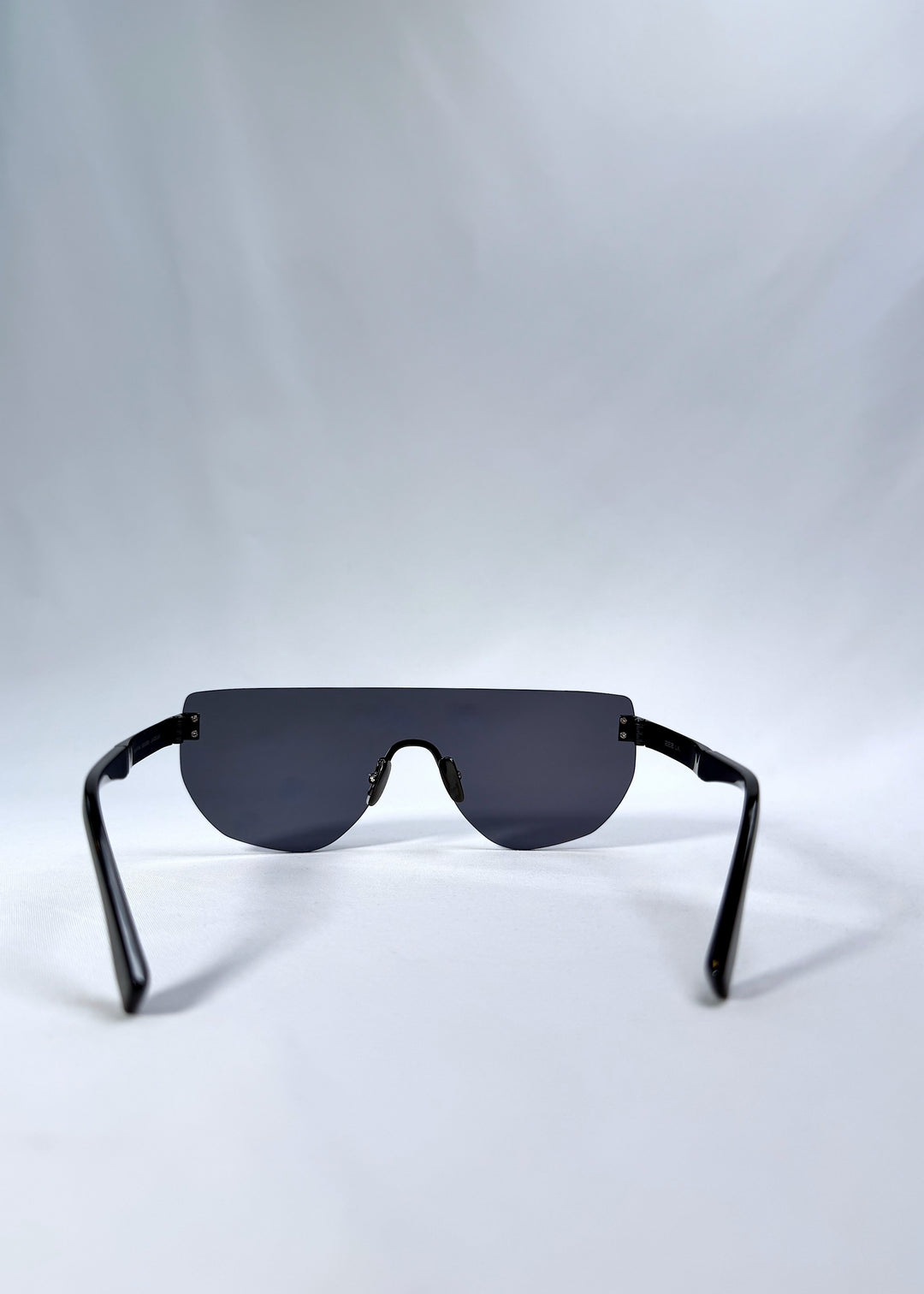Back view of Aegis Field sunglasses in Mercury Shadow, featuring one-piece titanium shield frame and silver mirrored lens, showing the inside frame and open temples.