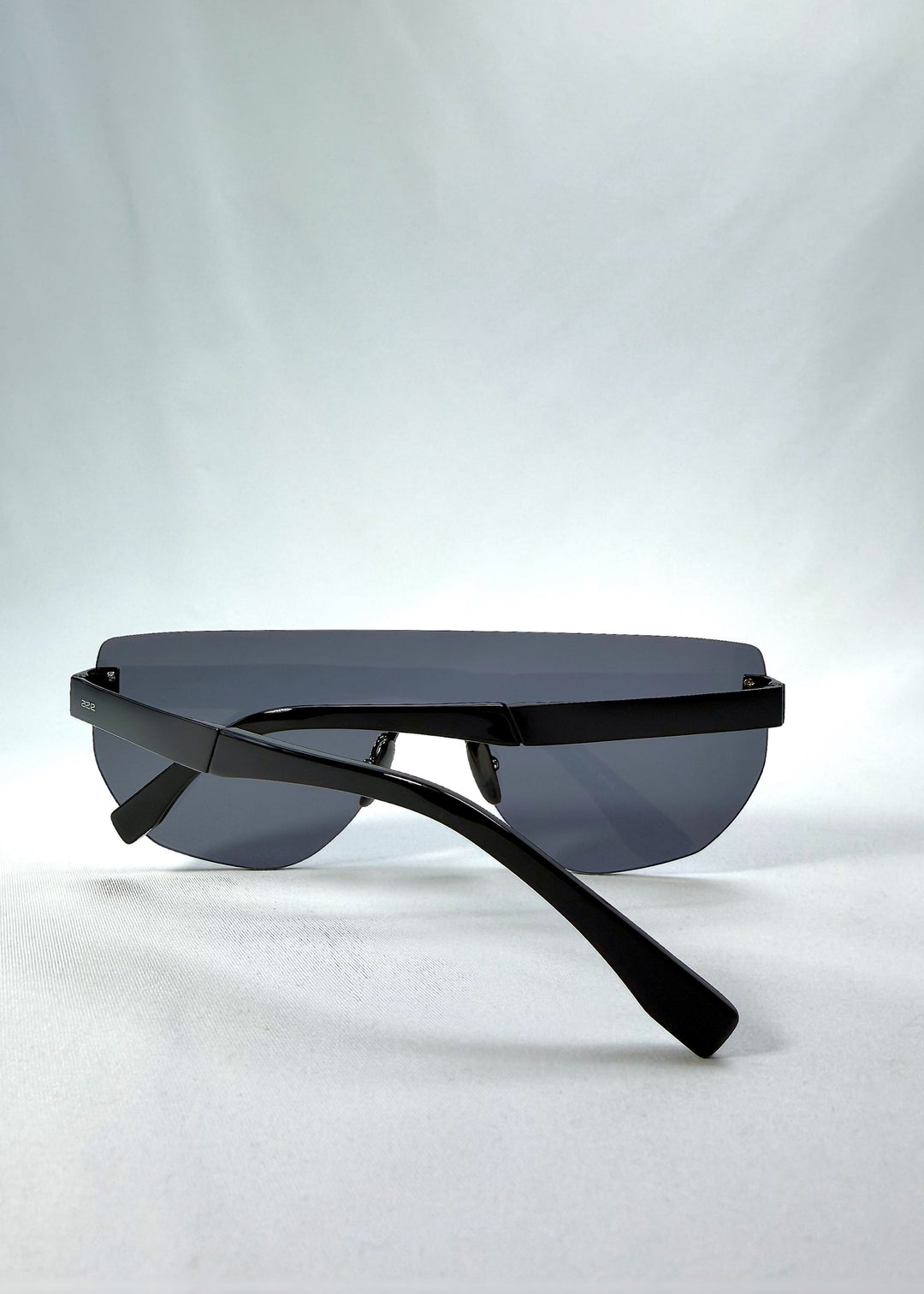 Folded view of Aegis Field sunglasses in Mercury Shadow, featuring one-piece titanium shield frame and silver mirrored lens, showing the folded temples and frame profile. 